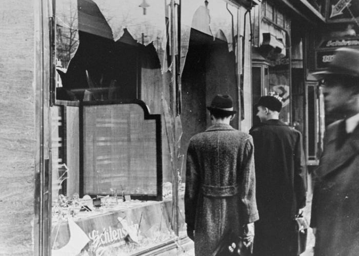 Немцы пройти мимо разбитой витрине еврейской собственности бизнеса, которая была разрушена во время хрустальной ночи