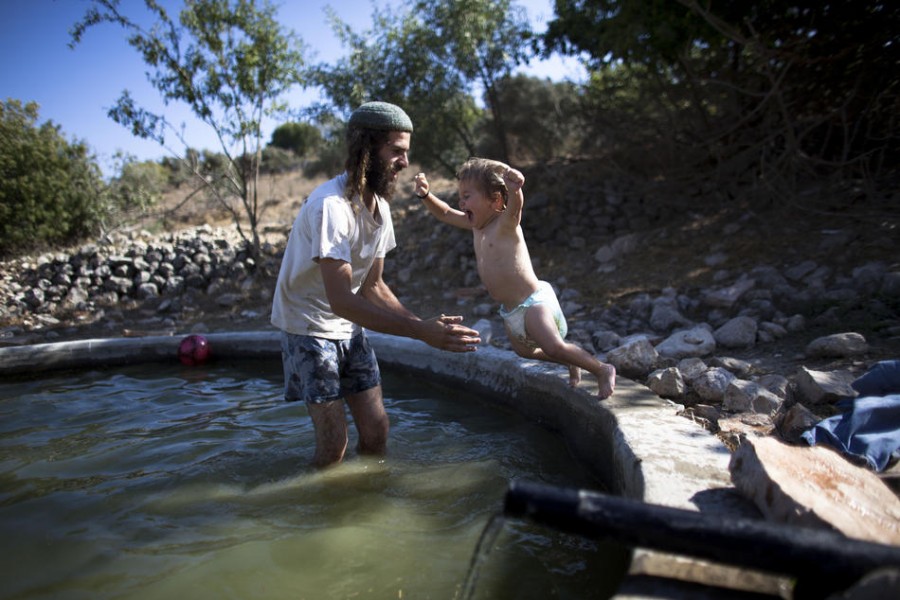 Израильтянин Ехуда Кохен из Хават Гилад купается с сыном в бассейне