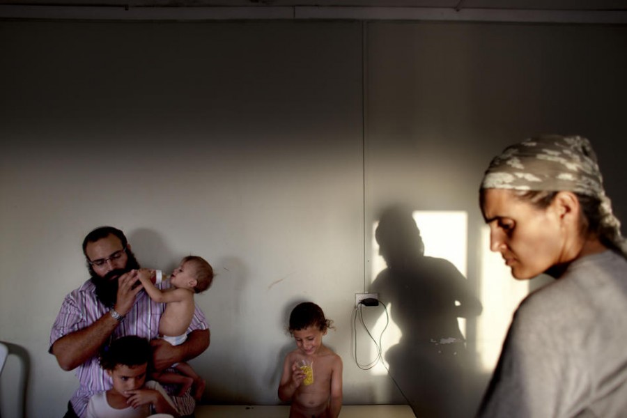 Израильский поселенец Ехуда Шимон и его жена Илана с детьми в своем доме в поселке Нават Гилад